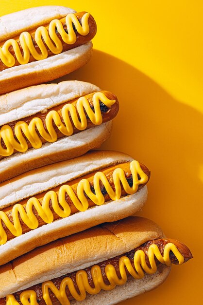 Gegrillte Hot Dogs vom Grill mit gelbem amerikanischen Senf auf dunklem Holzhintergrund