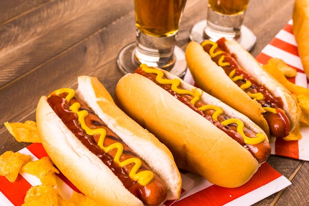 Gegrillte Hotdogs mit Senf und Ketchup auf dem Tisch mit Fassbier.