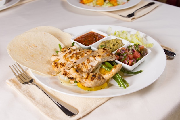 Gegrillte Hühnchen-Fajitas auf Teller am Gedeck im Restaurant