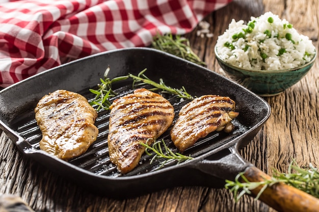 Gegrillte Hühnerbrust auf gegrillter Pfanne mit Reis und grünen Erbsen.