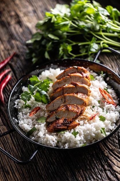 Gegrillte Hühnerbrust in einer Pfanne mit Jasminreis und Chilischoten