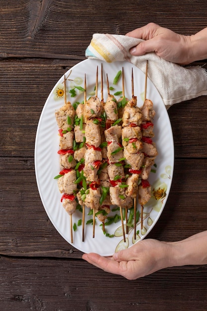 Gegrillte Hühnerspieße in weiblichen Händen