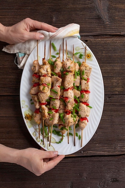 Gegrillte Hühnerspieße in weiblichen Händen