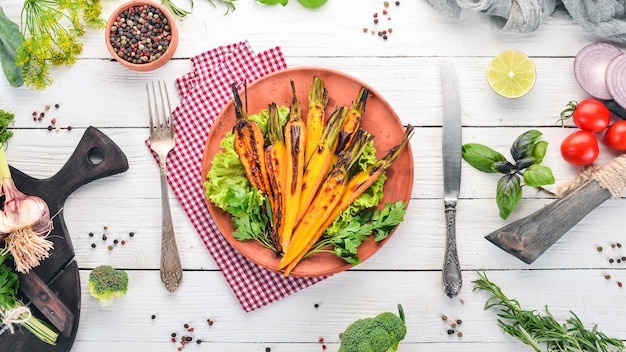 Gegrillte Karotte in einem Teller mit Gemüse Auf einem hölzernen Hintergrund Ansicht von oben Kopieren Sie Platz