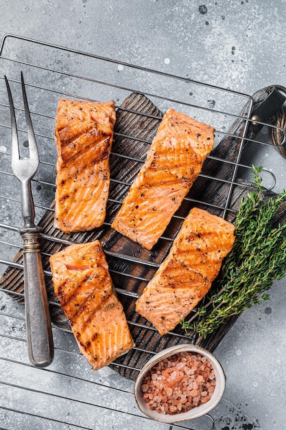 Gegrillte Lachsfiletssteaks mit Salzpfeffer und Kräutern auf dem Grill Grauer Hintergrund Ansicht von oben