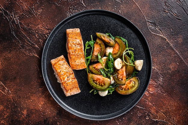 Gegrillte Lachsfiletsteaks mit Rucola und Tomatensalat auf einem Teller