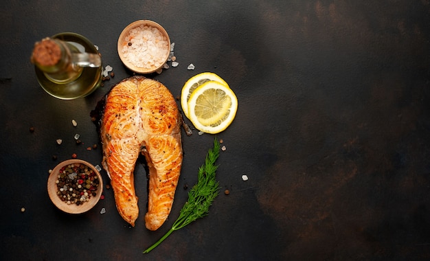 Gegrillte Lachssteaks mit Gewürzen, Kräutern, Salz und Zitrone auf einem Steinhintergrund mit Kopierraum für Ihren Text