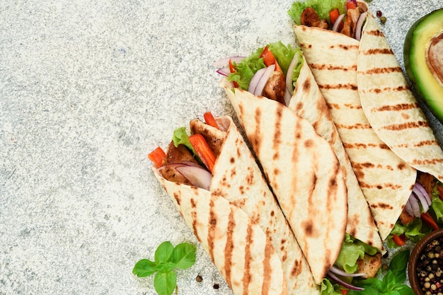 Gegrillte mexikanische Tortilla mit Gemüse auf einem konkreten Hintergrund. Von oben betrachten.