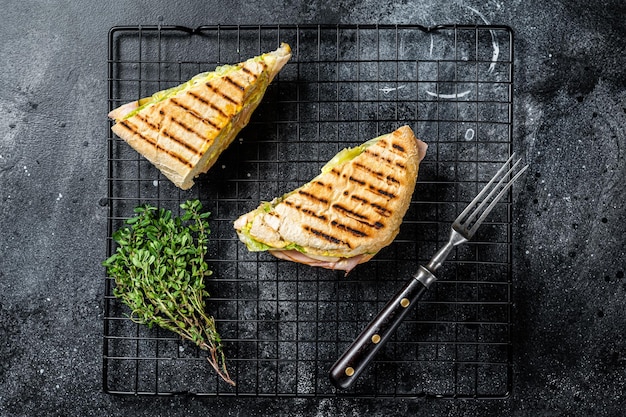 Gegrillte Panini mit Prosciutto-Schinkensalat und Käse Draufsicht auf schwarzen Hintergrund