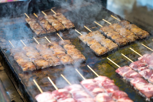 Gegrillte quadratische japanische Rindfleischstangen werden auf der großen Pfannenplatte mit Rauch herum angeordnet