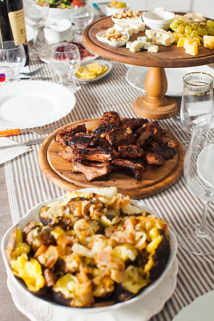 Gegrillte Rippchen und Backkartoffeln auf dem servierten Tisch in der Küche und Käseplatte