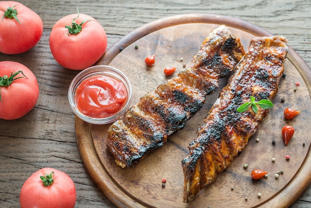 Gegrillte Schweinerippchen mit Tomaten auf dem Holzbrett