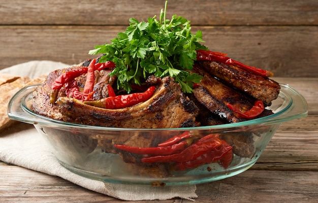 Gegrillte Schweinesteaks am Knochen liegen in einer transparenten Glasplatte