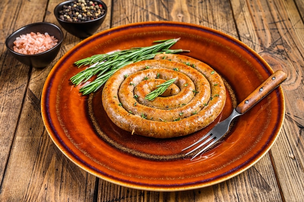 Gegrillte Spiralwurst aus Schweine- und Rindfleisch auf einem rustikalen Teller. Holztisch. Draufsicht.