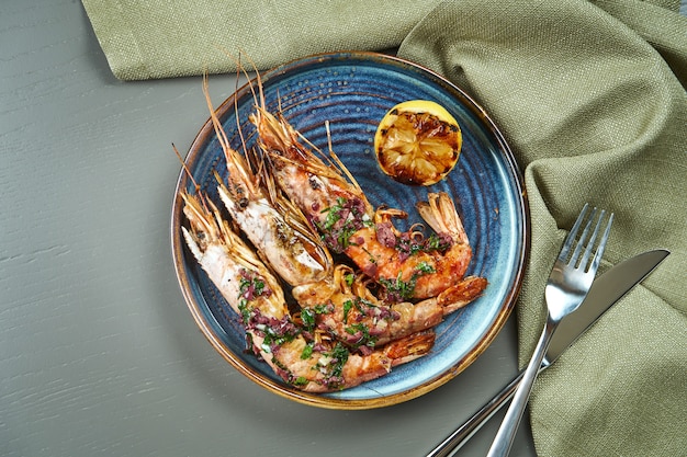 Gegrillte Tigergarnelen mit Zitrone in einem blauen Teller auf einem Holztisch. Luxus Meeresfrüchte Draufsicht,