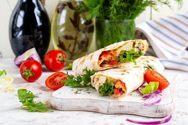 Gegrillte Tortilla mit Hühnchen und frischem Gemüse auf weißem Holzbrett Hühnerburrito mexikanisches Essen Gesundes Essen Konzept