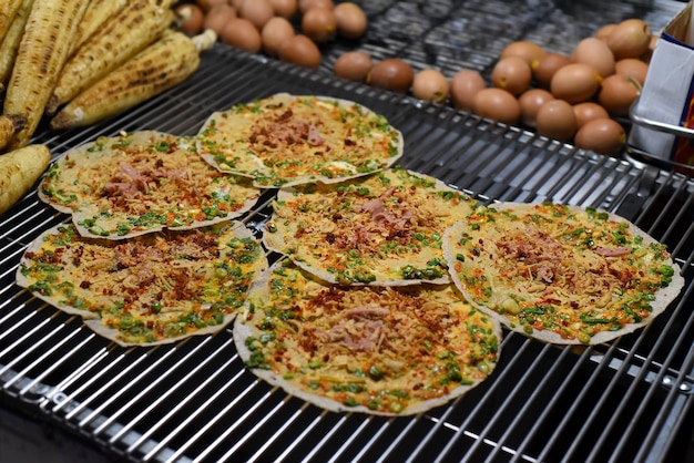 Gegrillte vietnamesische Pizza mit Eiern, Würstchen und Saucen auf dem vietnamesischen Nachtmarkt in Da Lat