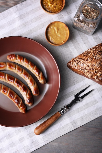 Gegrillte Würstchen auf dem Teller mit Brot auf dem Tisch hautnah