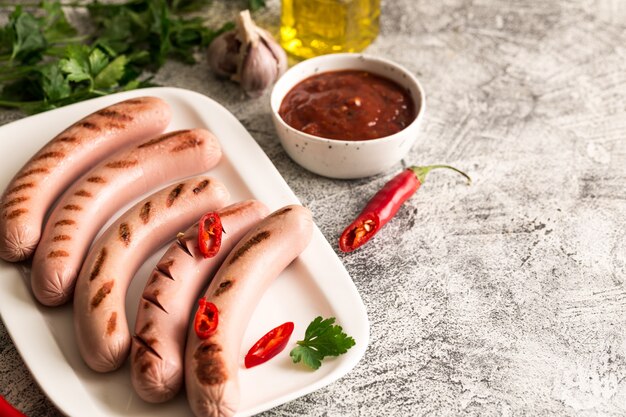 Gegrillte Würstchen mit Ketchup, Kräutern und Chilischoten