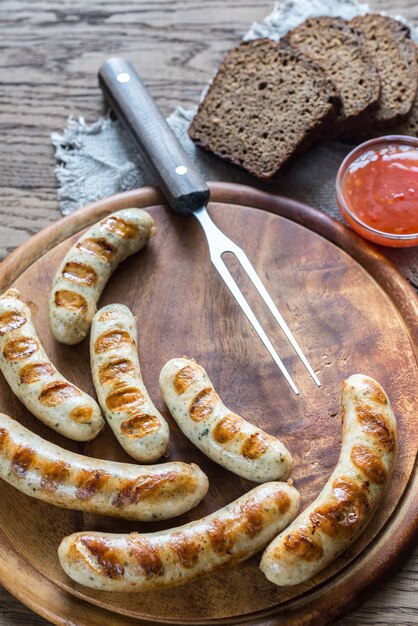 Gegrillte Würstchen mit scharfen Saucen auf dem Holzbrett