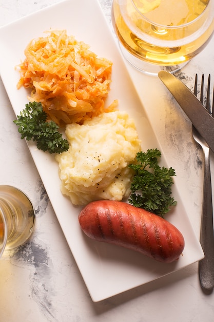 Gegrillte Würstchen und Kartoffeln mit einem Glas Bier