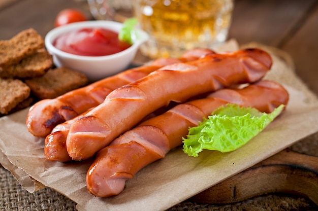 Foto gegrillte würste, cracker und bier auf einem holztisch in der rustikalen art.