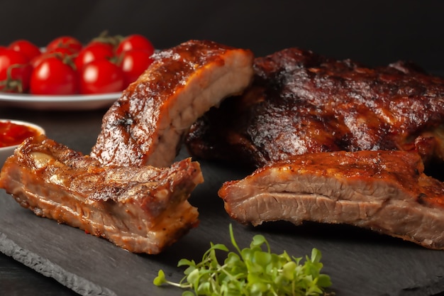 Gegrillte würzige Rippchen, serviert mit scharfer Chilisauce und frischen Tomaten