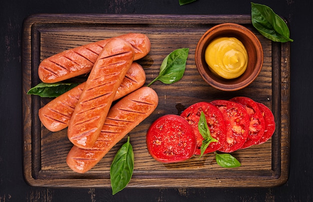 Gegrillte Wurst mit Tomaten, Basilikumsalat und roten Zwiebeln. Grillmenü. Draufsicht