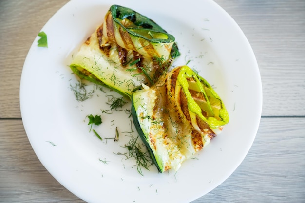 Gegrillte Zucchinistücke mit Knoblauchsauce auf einem weißen Teller