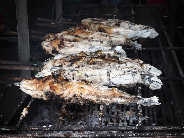 Gegrillter Fisch auf Eisengitter auf Holzkohleofen