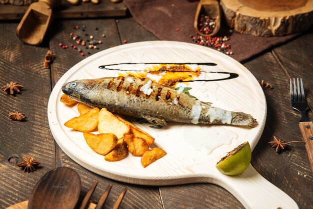 Gegrillter Fisch mit Kartoffeln auf dem Holzbrett