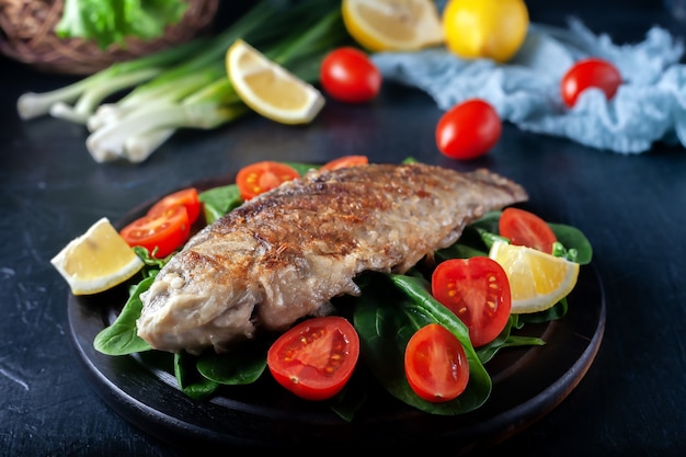 Gegrillter Fisch mit Tomatenspinat auf einem Holzbrett leckeres und leichtes Abendessen