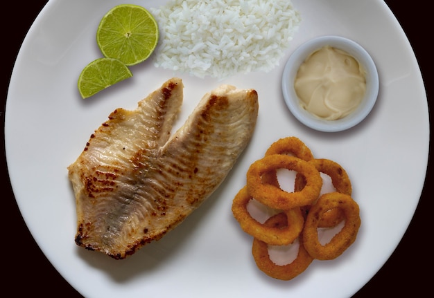 Gegrillter Fisch Reis Zwiebelringe Zitrone und Soße an der Seite