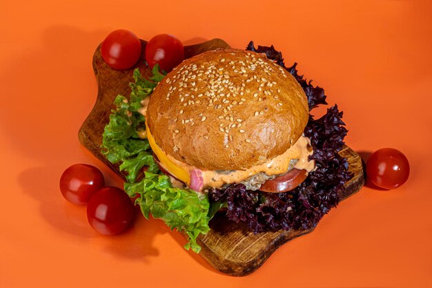 Gegrillter frischer Burger mit Rindfleisch-Pastetchen, Tomaten, Käse, Gurke und Salat auf Farbe