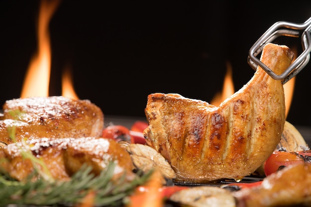 Gegrillter Hähnchenschenkel mit verschiedenem Gemüse auf dem brennenden Grill