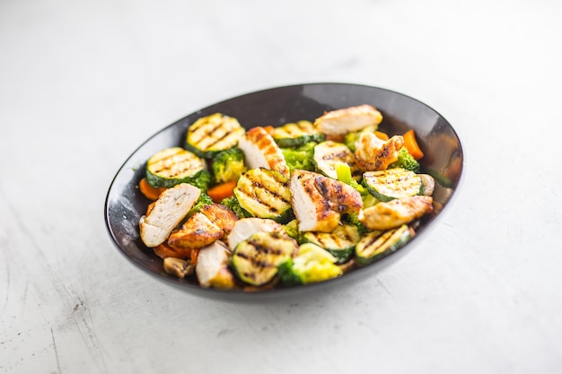 Gegrillter Hühnerbrust-Zucchini-Brokkoli und Karotte in schwarzer Platte. Griechisches oder mediterranes Essen.