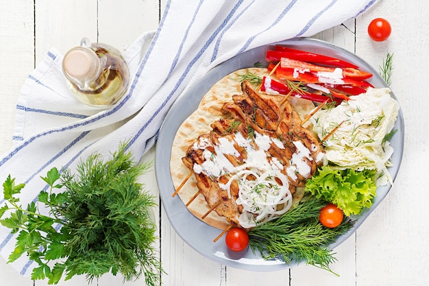 Gegrillter Hühnerkebab mit Pita, frisches Gemüse auf einem weißen Tisch