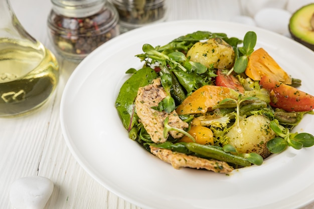 Gegrillter Hühnersalat Tomaten Kartoffeln und Grüns Auf einem weißen Teller und einem weißen Tisch