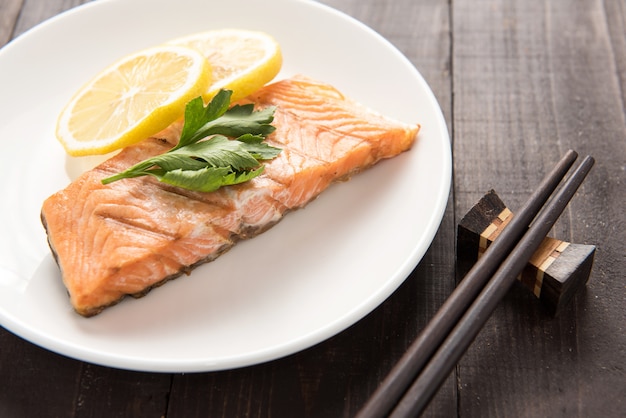 Foto gegrillter lachs von oben mit zitrone auf teller.