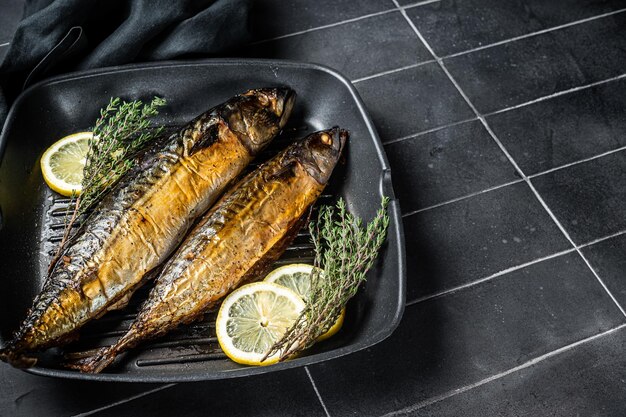 Gegrillter Makrelenfisch mit Zitronenkräutern und Gewürzen in einer Pfanne Schwarzer Hintergrund Draufsicht Kopierbereich