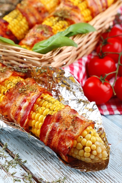 Foto gegrillter, mit speck umwickelter mais auf dem tisch in der nähe