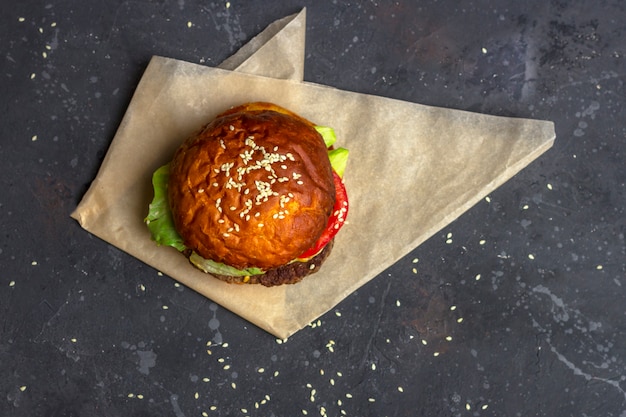 Gegrillter Rindfleischburger mit Salat und Tomate, serviert auf Pergamentpapier