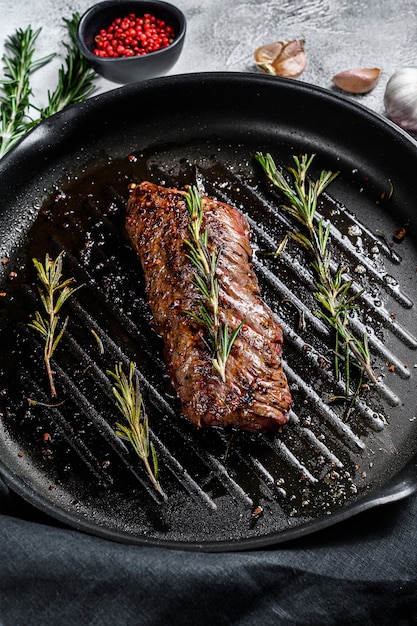 Gegrillter Rock, Machetensteak in einer Pfanne. Marmorfleisch Rindfleisch. Graue Oberfläche. Draufsicht