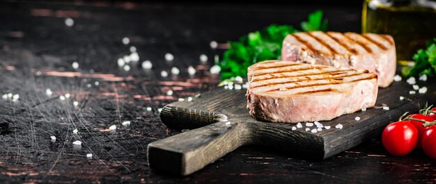 Gegrillter Thunfisch auf einem Schneidebrett mit Petersilie und Tomaten