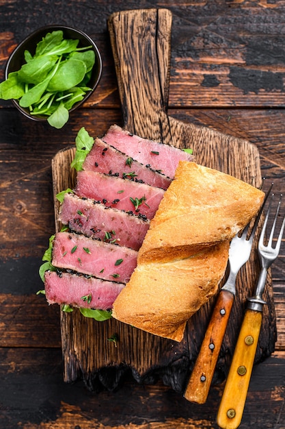 Gegrilltes Ahi Thunfisch Steak und Avocado Sandwich mit Rucola auf einem Schneidebrett.