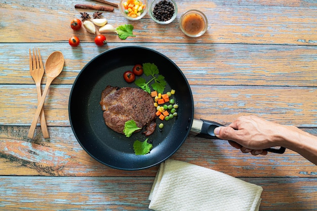 Gegrilltes Black Angus Steak auf Grilleisenpfanne auf Holzuntergrund