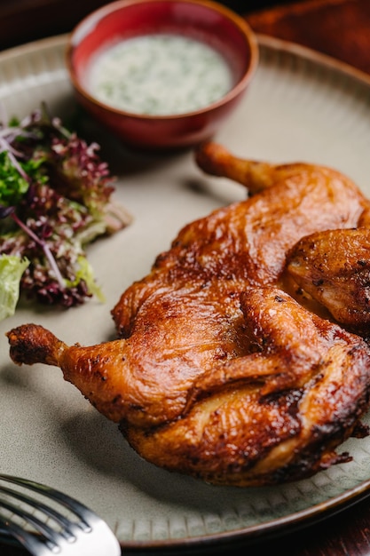 Gegrilltes Brathähnchen Tabaka mit Knoblauchsoße und Salat auf einem Holztisch Nahaufnahme