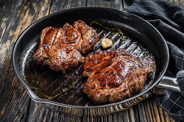 Gegrilltes Chuck Eye Roll Steak in einer Pfanne. Dunkler Hintergrund.