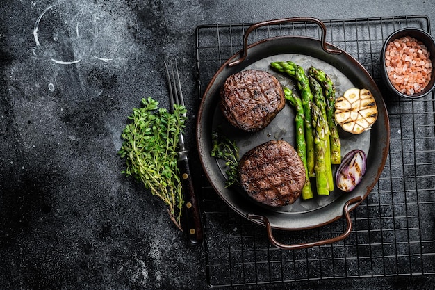 Gegrilltes Filet Mignon Steak mit geröstetem Spargel Schwarzer Hintergrund Draufsicht Kopierbereich