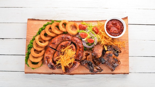 Gegrilltes Fleisch auf dem Brett Wurstrippen und frisches Gemüse Auf einem Holztisch Draufsicht Kopieren Sie Platz